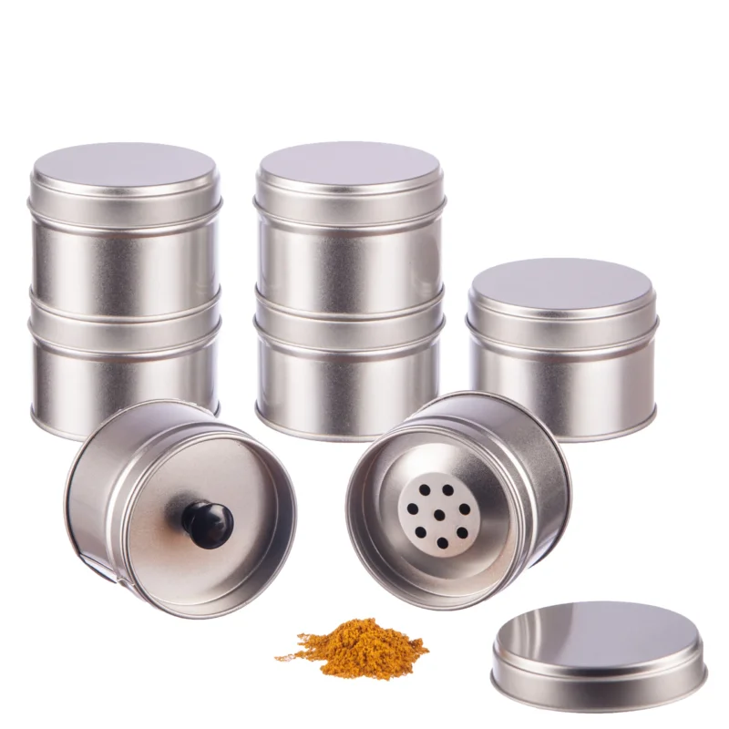 12 Gewürzdosen aus Weißblech mit Aromadeckel und 12 Etiketten, eine Dosis offen, Gewürz davor.