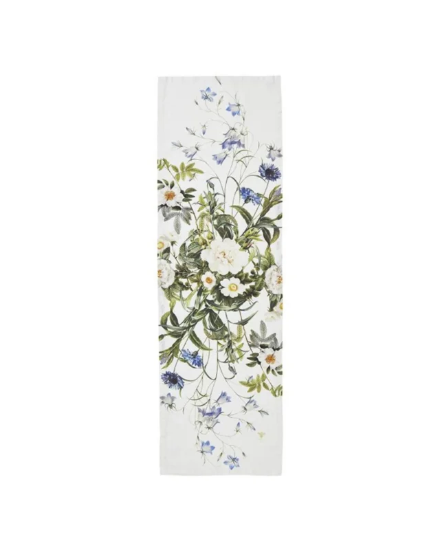 Ein schmaler Tischläufer aus Leinen mit zarten weißen und blauen Blumenmotiven sowie grünen Blättern auf hellem Grund. Die natürliche, leicht strukturierte Oberfläche des Leinens unterstreicht die ländliche Eleganz des floralen Designs von Koustrup & Co.