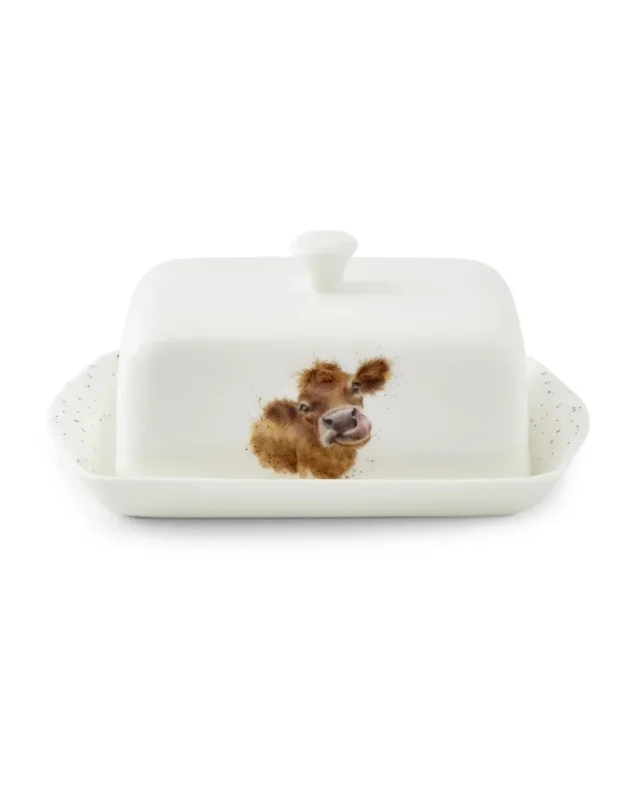 Frontansicht der Kuh Butterdose "Royal Worchester" aus Porzellan von Wrendale Designs vor weißen Hintergrund. Das Motiv zeigt eine Kuh mit herausgestreckter Zunge.