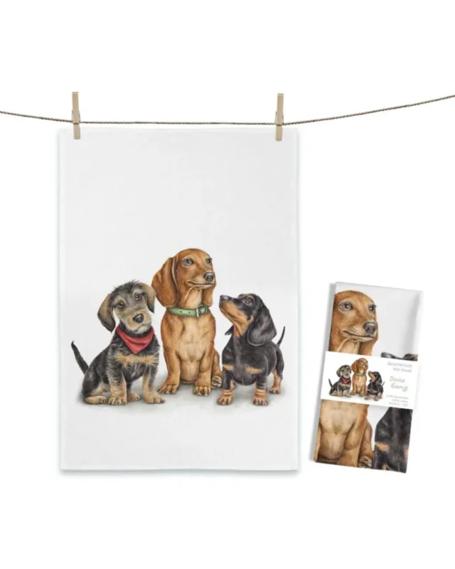 Dackel Geschirrtuch Doxie Gang von Maluu mit drei illustrierten Dackeln nebeneinander auf hellem Hintergrund aufgehängt an einer Leine