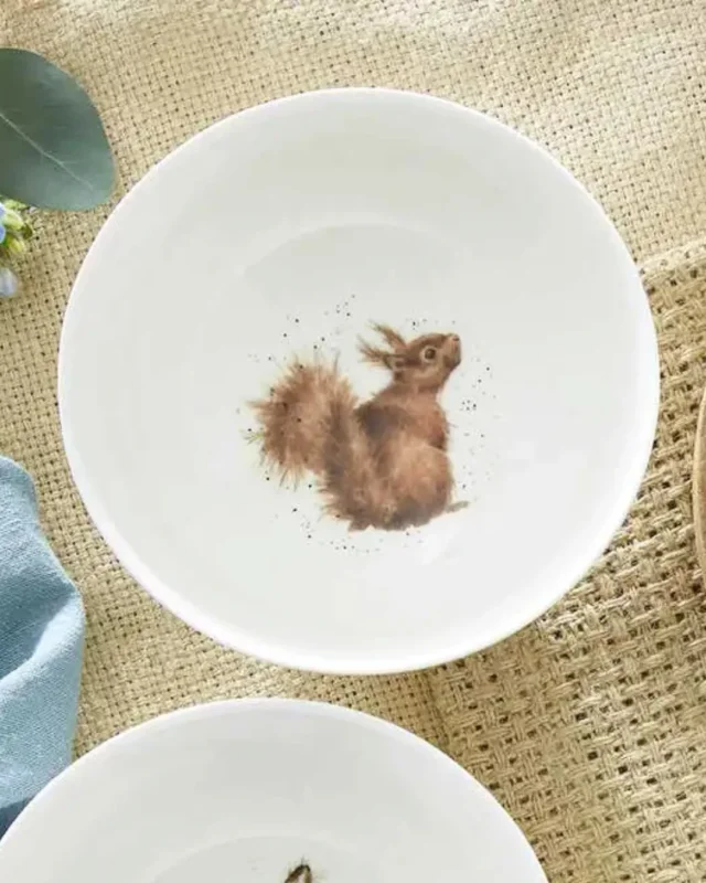 Eichhörnchen Bowl "Royal Worchester" von Wrendale Designs auf einem beeckten Tisch. Der Teller selbst ist weiß. Das Motiv zeigt ein Eichhörnchen welches neugierig nach hinten in die Kamera schaut.