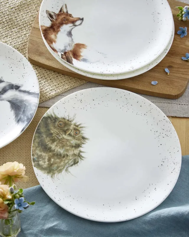 Weißer Eulen Essteller "Royal Worchester" von Wrendale Designs auf bedeckten Tisch. Das Motiv zeigt eine Eule an der linken Seite welche in die Kamera schaut. Die Seiten des Tellers sind schwarz gepunktet. Im Bild sind noch 2 andere "Royal Worchester" Teller zu sehen.