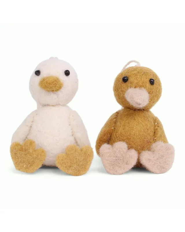 Zwei handgefertigte Filzanhänger in Entenform von Gry & Sif, eine Ente in Naturweiß mit gelbem Schnabel und Füßen sowie eine Ente in warmem Braun mit hellen Akzenten, beide sitzend vor hellem Hintergrund.