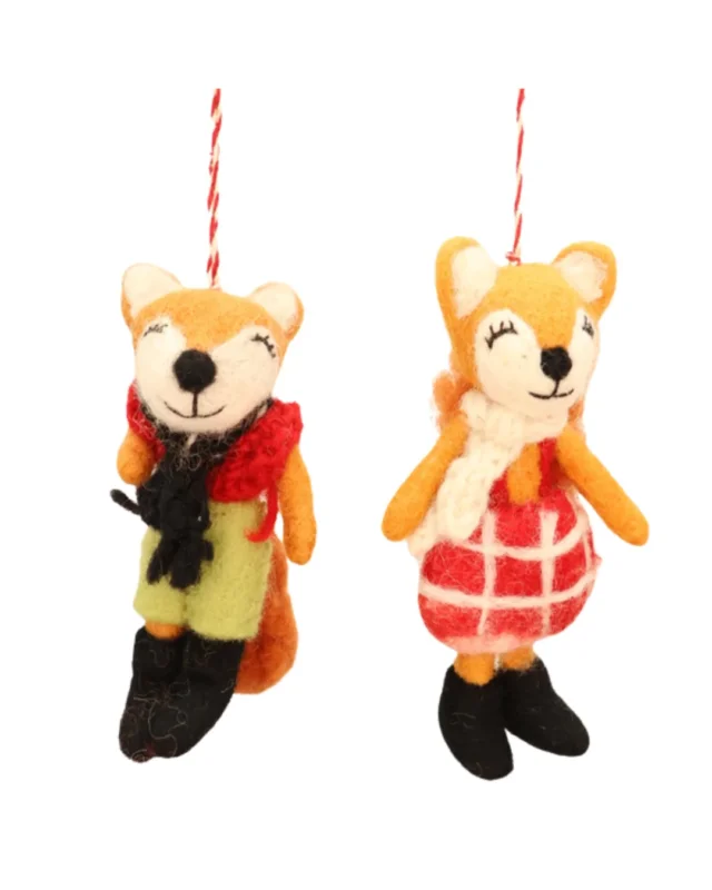Winrterfüchse Filzanhänger "Naomi & Nils" von Grace und Gloria. Rechts "Naomi" mit rot-weißer Latzhose, weißem Schal und schwarzen Schuhen und links daneben "Nils" mit grüner Hose, roter Strickweste, schwarzem Schal und schwarzen Stiefeln.