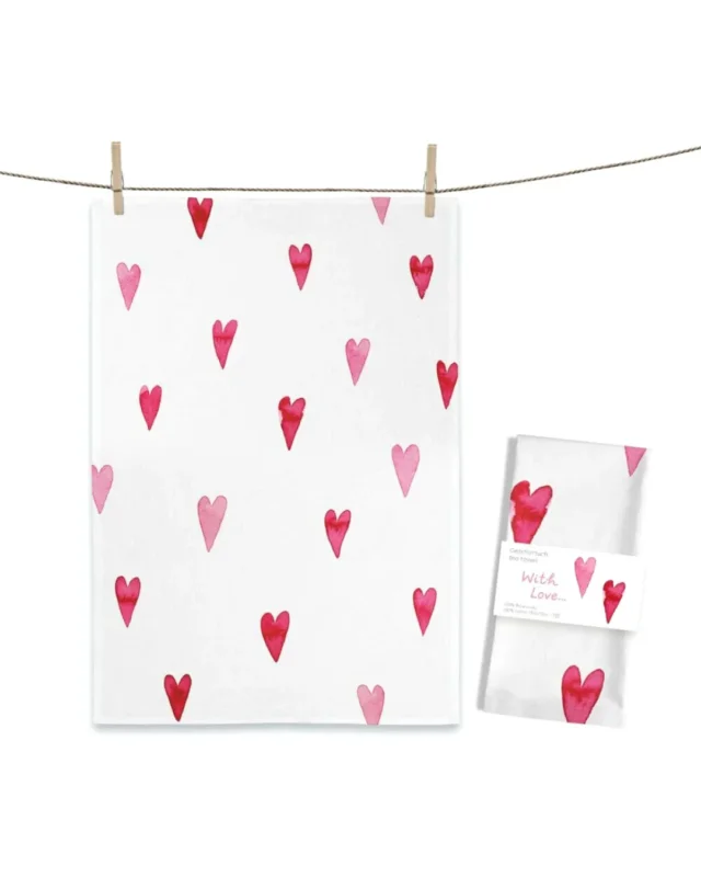 Herzchen Geschirrtuch „With Love“ von Maluu mit roten und rosafarbenen Herzen auf weißem Hintergrund, aufgehängt an einer Leine