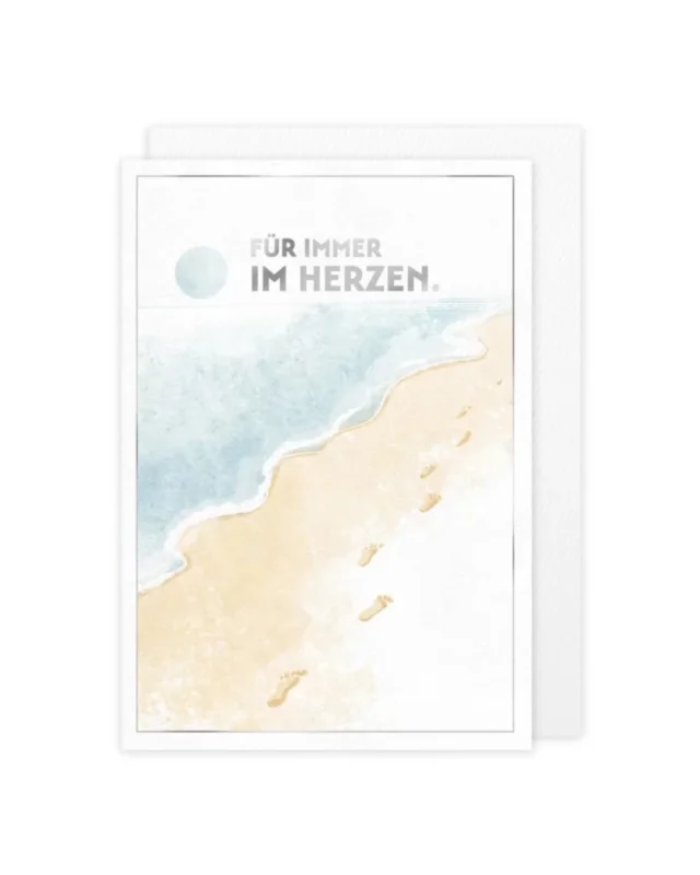 Die Grußkarte "Fußspuren im Sand" vom Grätz Verlag ist illustriert von Antje Therés Kral. In hellen Pastelltönen ist ein Strand mit ruhigem Meer und hellem beige-weißlichem Sand dargestellt. Ein paar Fußspuren sind im Sand zu erkennen. In der obereb Bildmitte steht "Für immer im Herzen".
