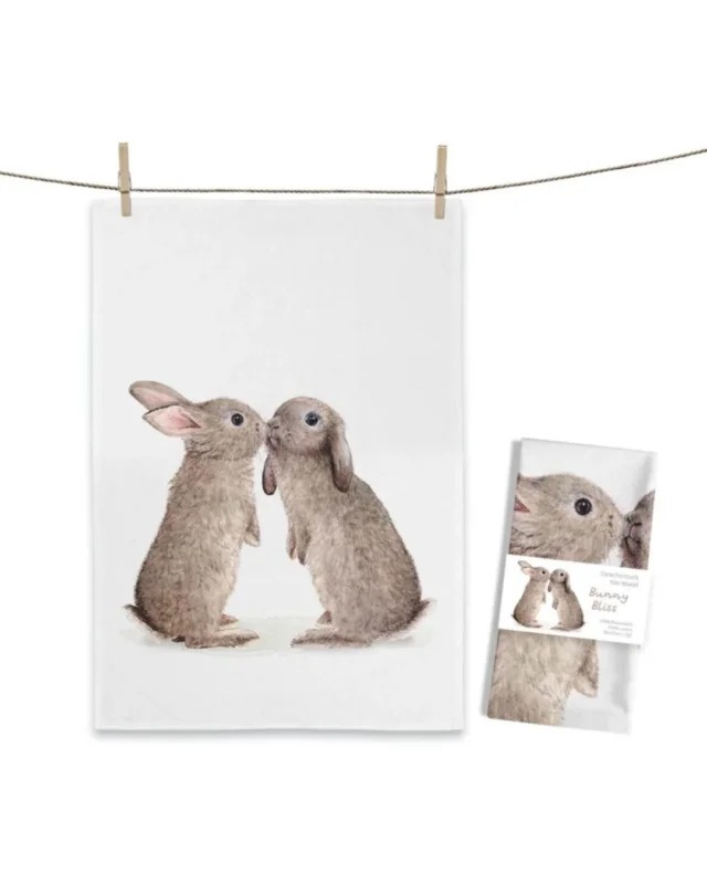 Kaninchen Geschirrtuch „Bunny Bliss“ von Maluu mit zwei sich zugewandten Kaninchen als Illustration auf weißem Baumwolltuch an Leine aufgehängt