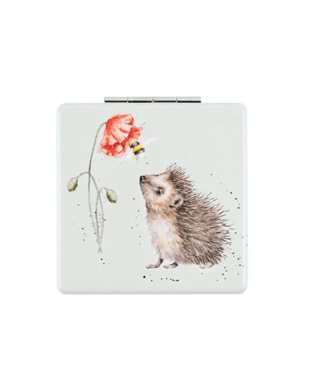 Vorderseite des Igel Taschenspiegel mit einer rot blühenden Mohnblume und zwei geschlossenen Mohnblumen. An der Blüte fliegt eine mit Blütenstaub behaftete Hummel, welche dabei von einem neugierigen, fast überraschten Igel beäugt wird. Das detailreiche Motiv von Hannah Dale ist in natürlichen Farben dargestellt und auf dem mintgrünen Untergrund des Klappspiegels aufgebracht.