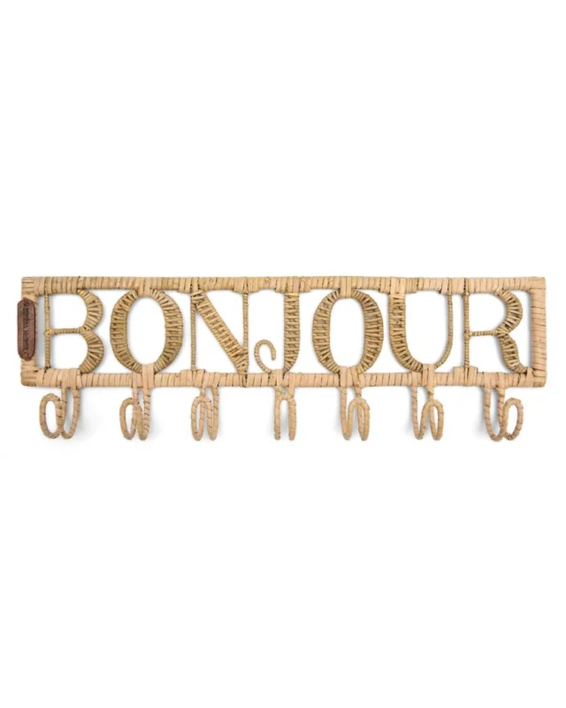 Diese Garderobe aus Rattan von Rivèra Maison besteht aus dem Schriftzug Bonjour und sieben Haken, die darunter angebracht sind.