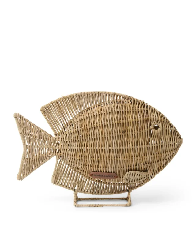 Rustic Rattan "Isola Fish Statue" vor weißen Hintergrund. Die Statue besteht fast vollständig aus Rattan. Sie Hat unten einen Ständer aus Rattan ist wie ein Fisch geformt und an der Seite steht "Riviera Maison".