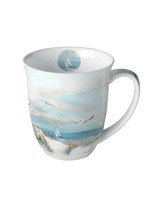 Weiße Keramik-Tasse mit maritimem Motiv (Dünen, Möwen, Segelboot) der Marke Ambiente, isoliert auf weißem Hintergrund.
