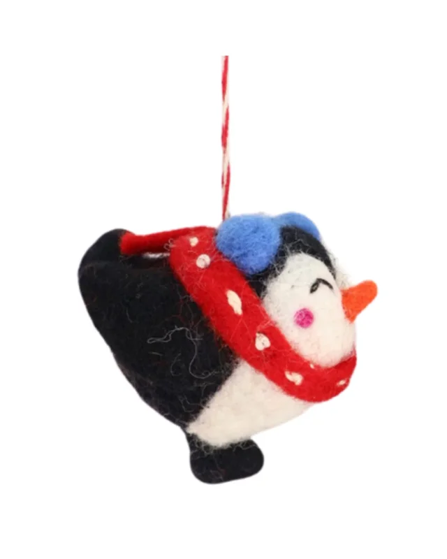 Seitansicht des handgefertigten Filzanhängers "Träumender Pinguin Pia" von Grace & Gloria mit rotem Schal und blauen Ohrwärmern, schwarzem Gefieder, weißem Bauch und orangefarbenem Schnäbelchen.