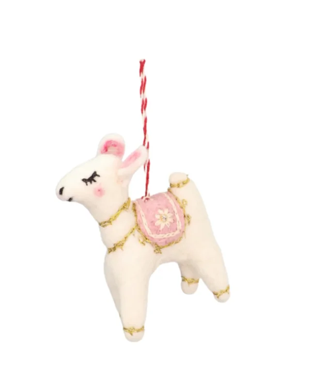 Seitansicht des handgefertigten Filzanhängers "Träumendes Lama Polly" von Grace & Gloria mit weißem Fell, goldenen Zierbändchen an den Beinen und am Hals und einer rosa Zierdecke auf dem Rücken.