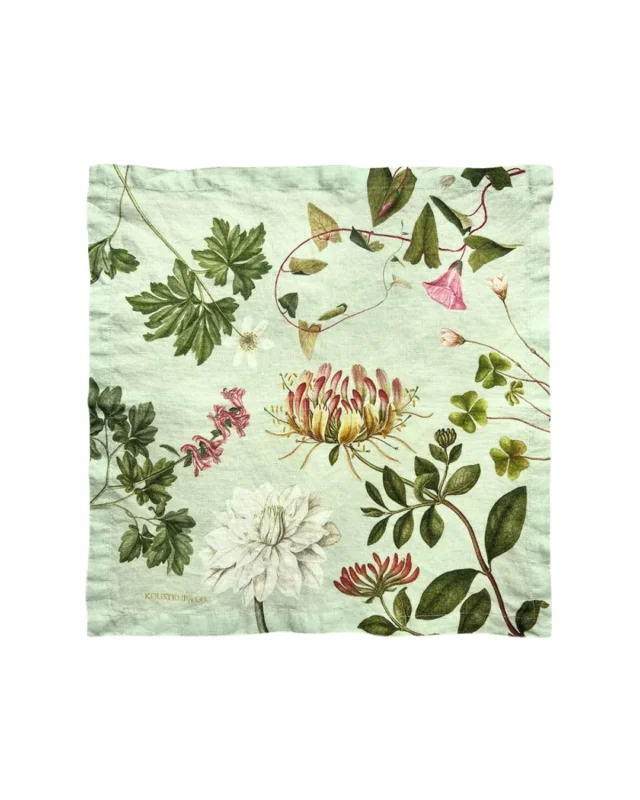 Grüne Stoffserviette mit rauer Oberfläche und Blumenmotiven auf weißem Hintergrund.
