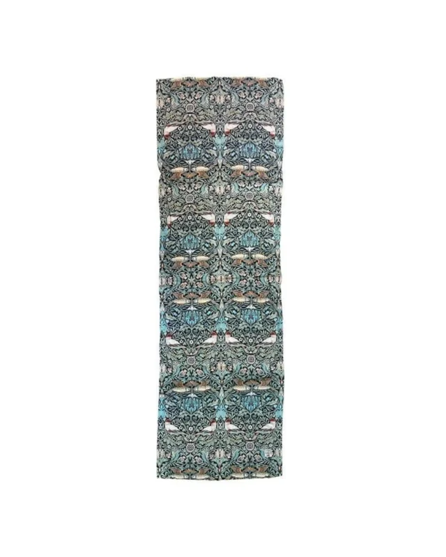 Ein schmaler Tischläufer aus Leinen mit dem "William Morris Bird"-Muster von Koustrup & Co., das Vögel und florale Ranken in Blau-, Grün- und Beigetönen zeigt. Die charakteristische, leicht strukturierte Oberfläche des Leinens unterstreicht die historische Eleganz des Designs.