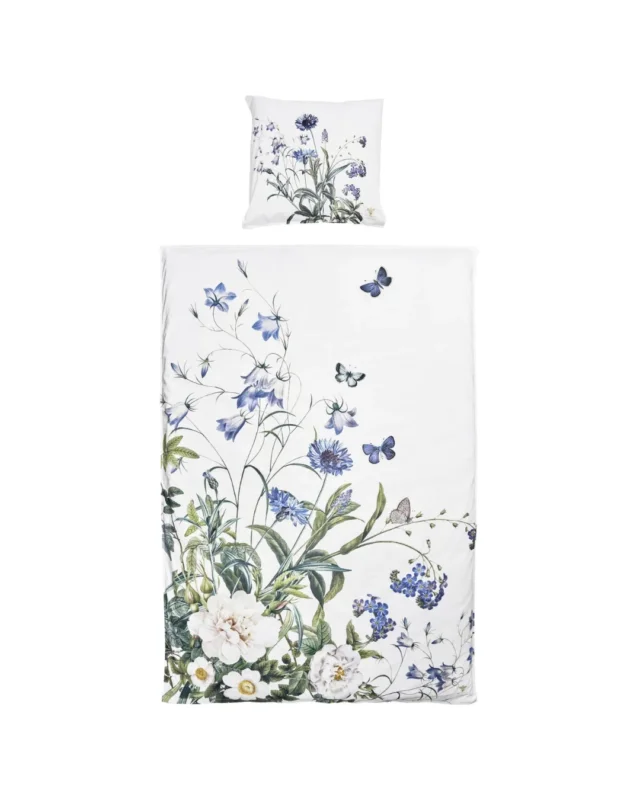 Bettwäsche „Blue Flower Garden“ von Koustrup & Co. mit handgezeichneten Blumenmotiven in Blau und Weiß, Kissen und Bettdecke auf weißem Hintergrund.
