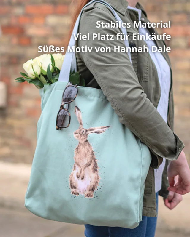 Hellgrüne Hasen-Einkaufstasche von Wrendale Designs getragen von einer Frau. Das Motiv ist ein aufrecht stehender Hase welcher neugierig in die Ferne guckt. An der Tasche hängt eine Sonnenbrille und es hängen weiße Tulpen raus.