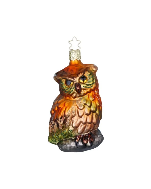 Detailreiche mundgeblasene Eule von Inge Glas. Die orange-bronze farbene Eule sitzt auf einem schwarzen Stein. Grün schimmernder Glitzer setzt Highlights in den Federn.