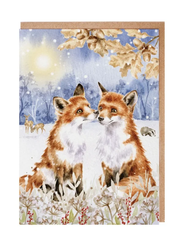 Weihnachtliche Fuchs Doppelkarte von Wrendale Designs. Zwei von Hannah Dale illustrierte Füchse sitzen unter einem braunen Eichenzweig in einer Schneelandschaft. Vor ihnen sind ein paar grün-weiße Pflanzen und rote Beeren zu sehen. Im Hintergrund halten sich zwei Rehe und ein Dachs auf. Der Mond leuchtet hell im leichten Schneetreiben.