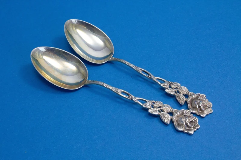 2 silver teaspoons with a rose pattern